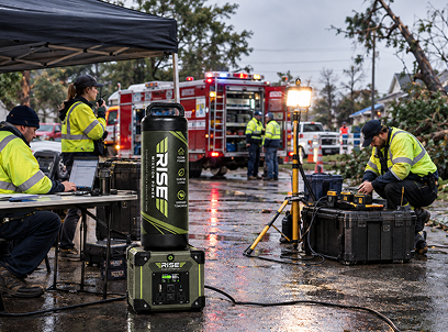 Emergency responders powering laptops and radios from a Rise portable system beside a fire truck after a storm